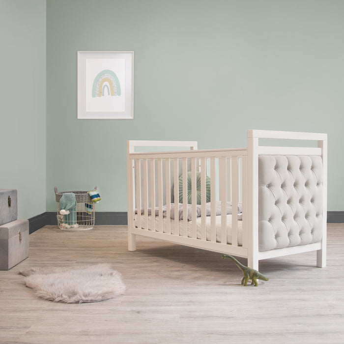 A serene nursery with a white crib set against calming green walls.