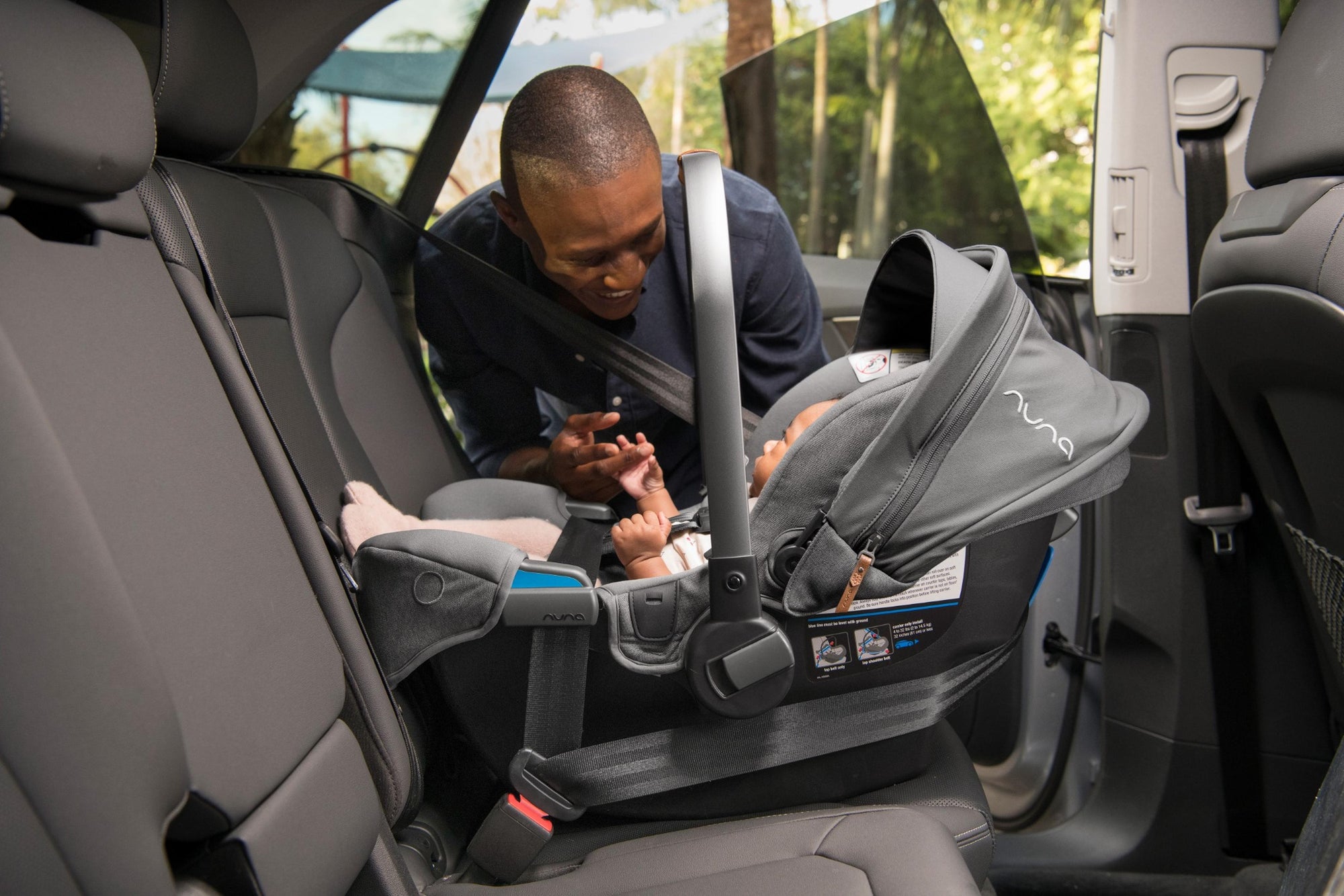 Rear-facing Nuna Pipa infant car seat properly installed with baby and parent interaction